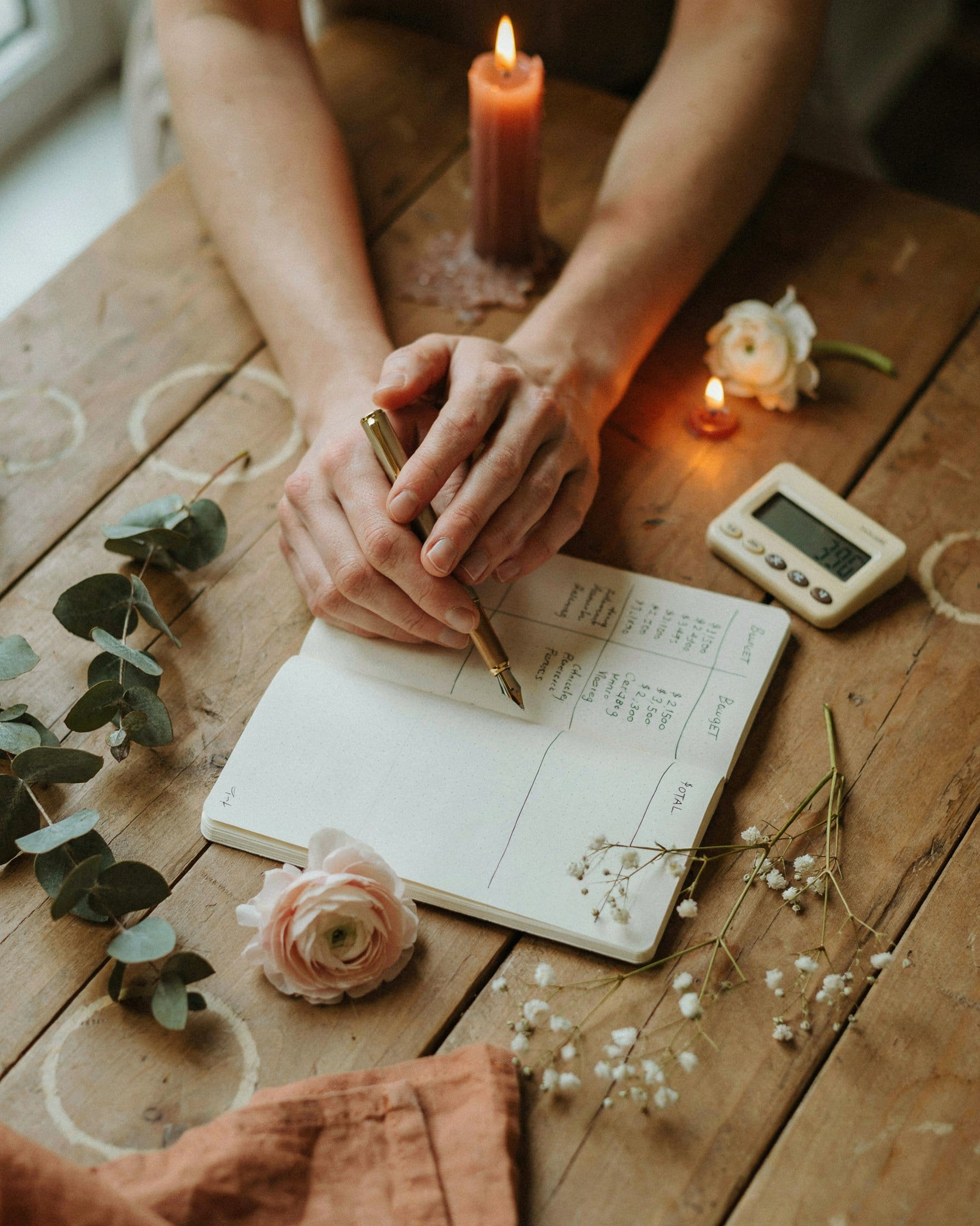 Couple planning their wedding budget together, notebook and flowers on a rustic table