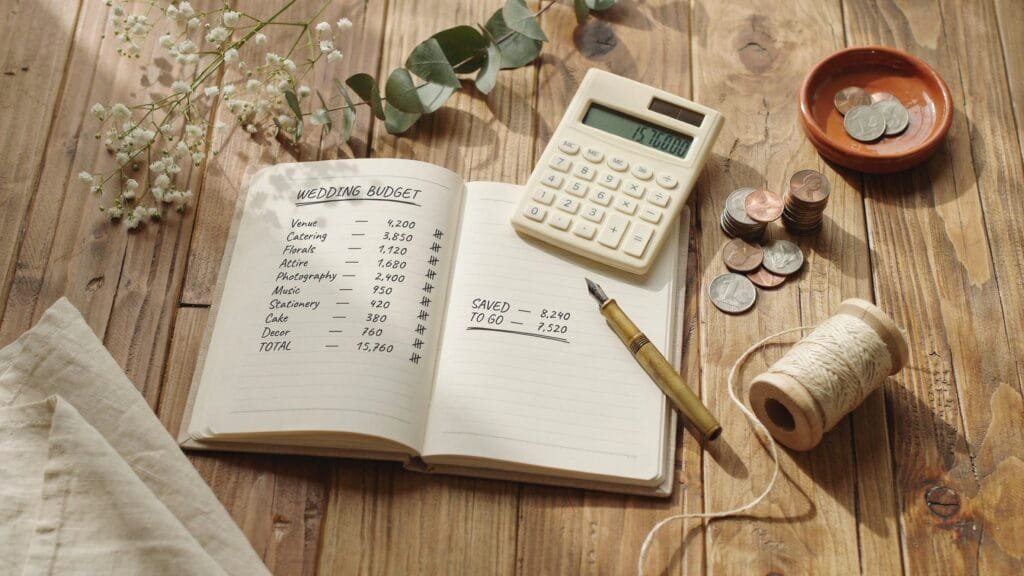 Wedding budget planning flat lay with notebook, calculator, and dried flowers
