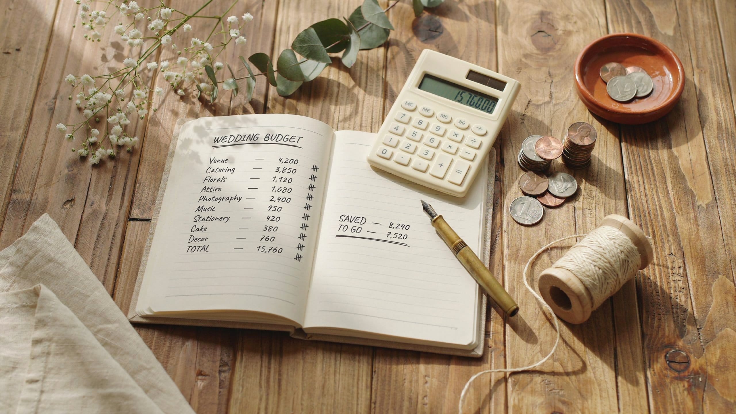 Wedding budget planning flat lay with notebook, calculator, and dried flowers