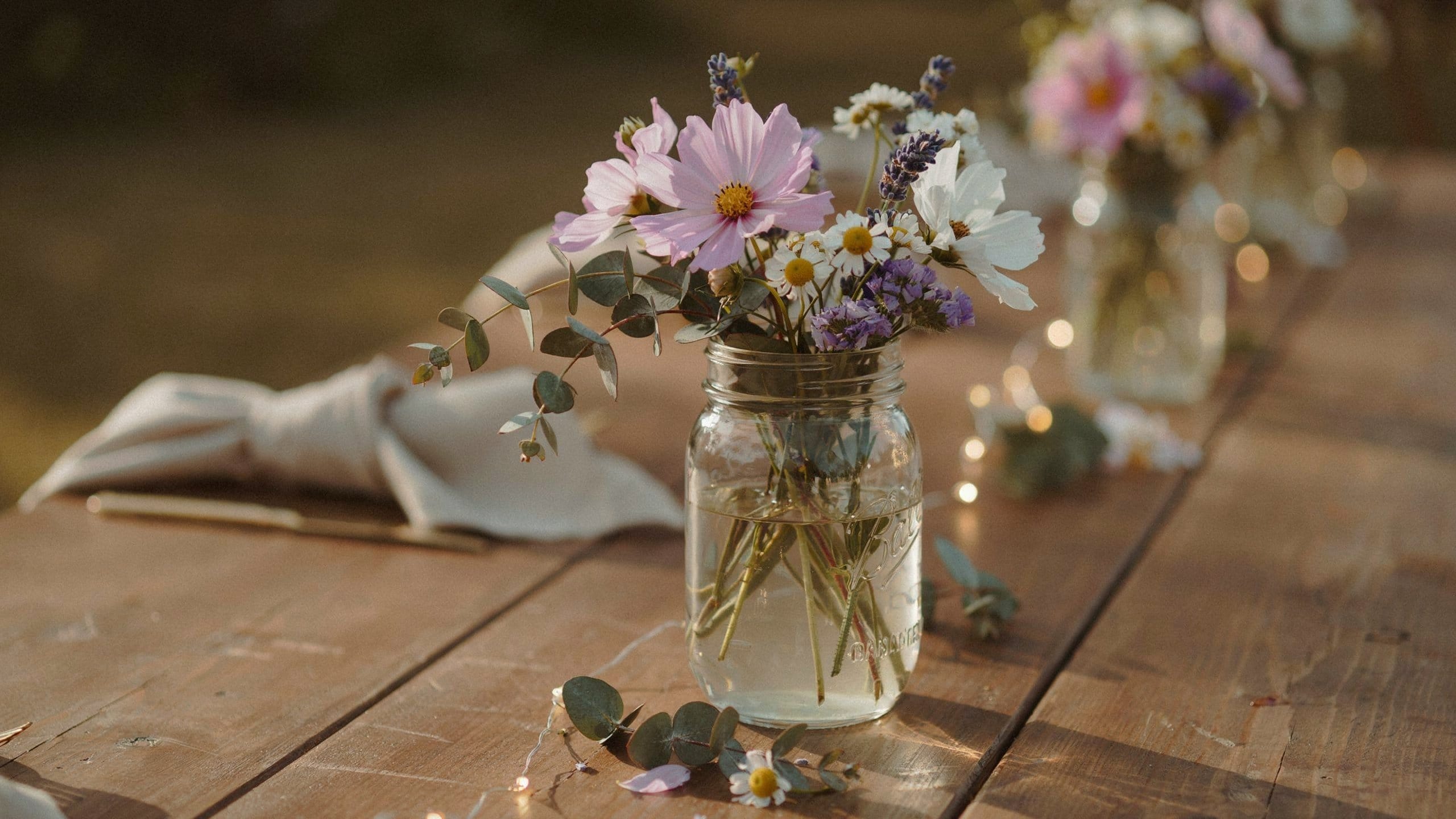 DIY mason jar wildflower wedding centerpiece on rustic wood table